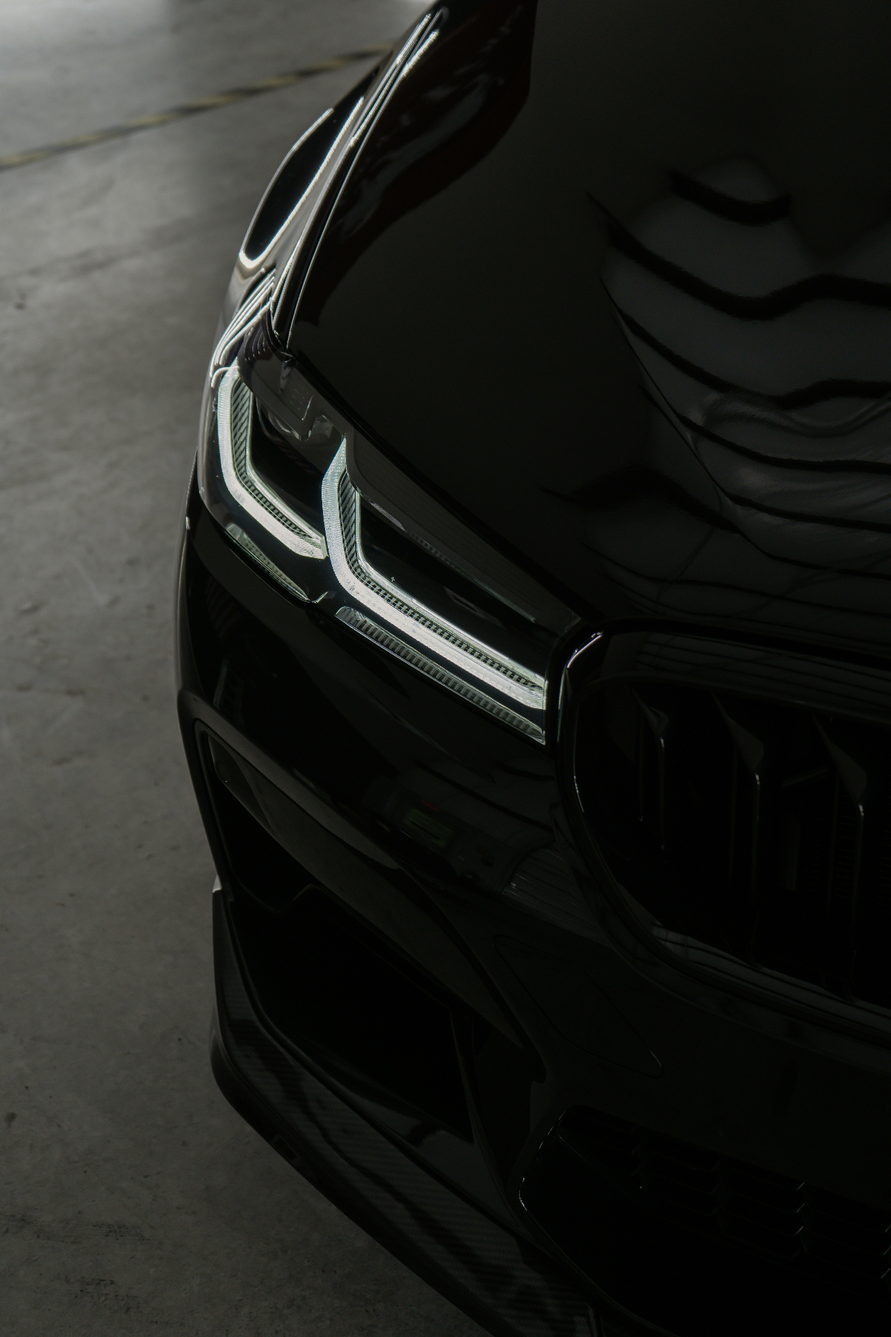 Schwarzer BMW mit spiegelglatter Front nach Politur und Keramikversiegelung – Scheinwerfer und Lack reflektieren wie ein Spiegel