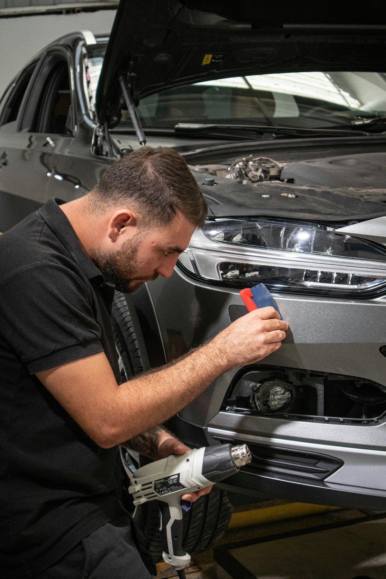 Detailer poliert und frischt ein schwarzes Kunststoff-Spiegelgehäuse am Auto auf